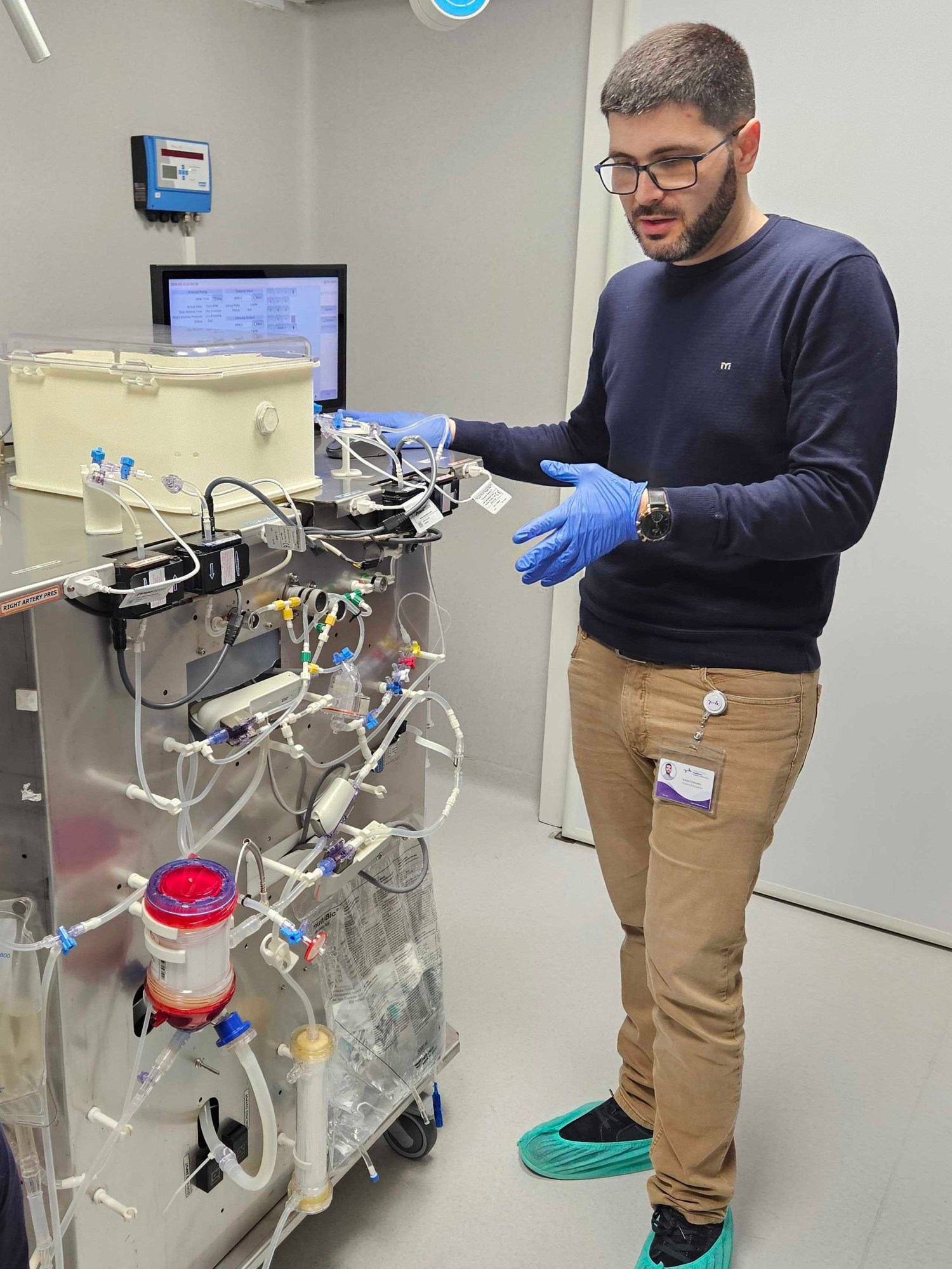 a person in gloves stands next to a machine with lots of tubing coming in and out of the metal exterior