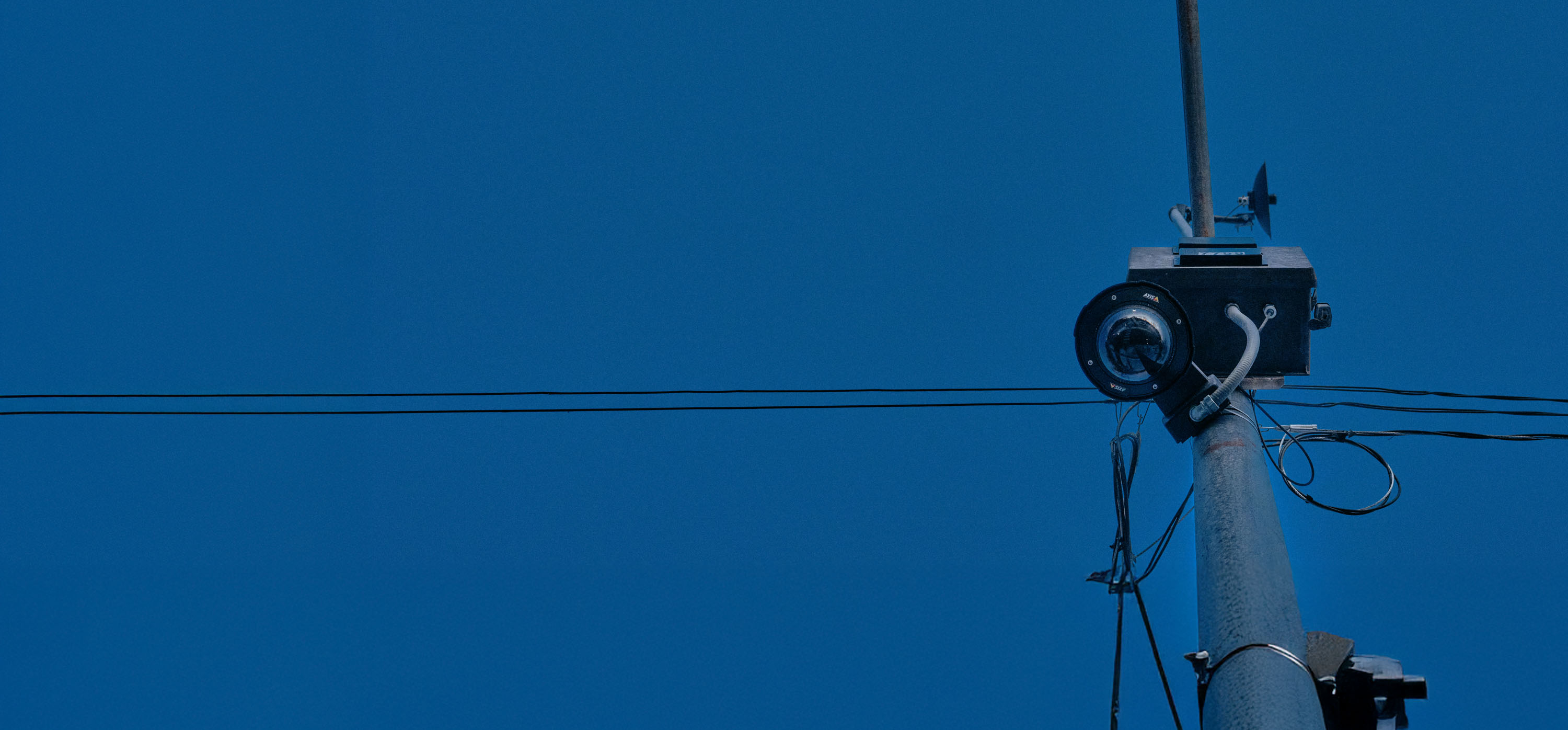 Surveillance camera on a pole against a dark blue sky