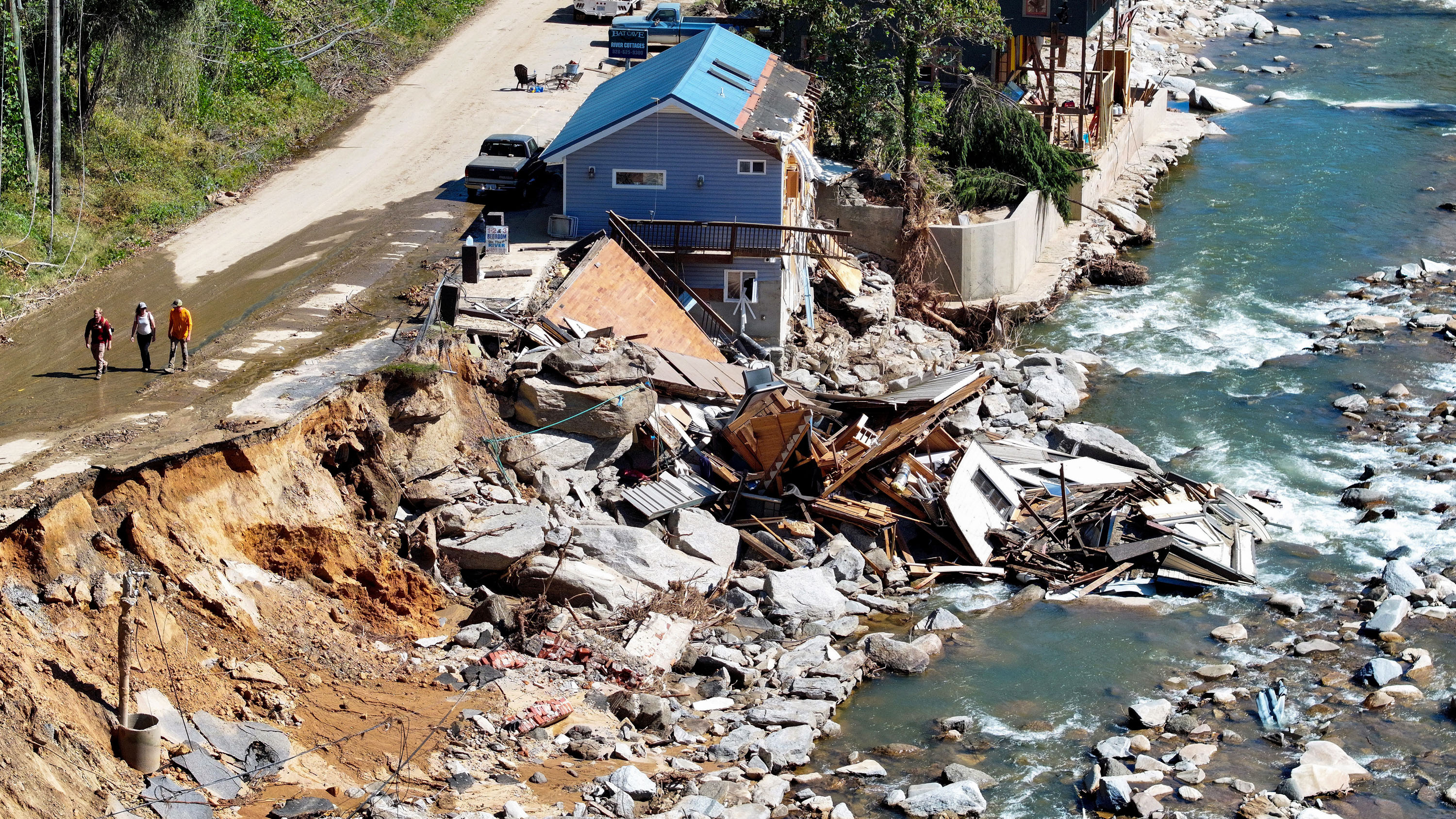 An aerial view of people walking past destroyed and damaged buildings in the aftermath of Hurricane Helene